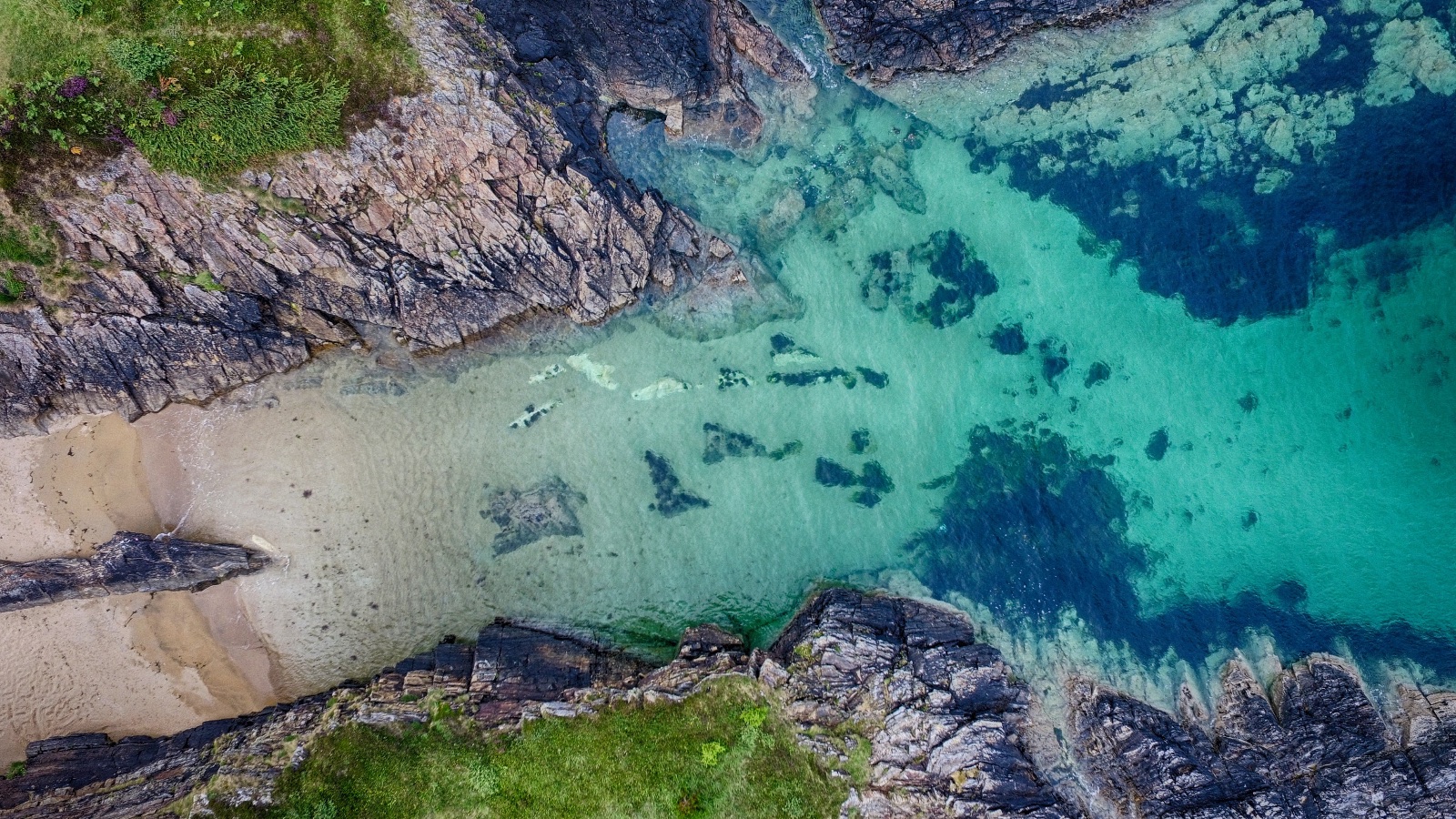 A small sandy cove between two arms of dark rock, 4:21 pm.