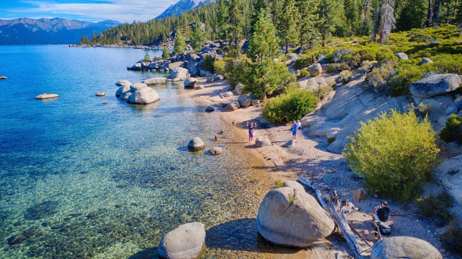 From the drone, a September morning in 2026: the beach, the boulders and the clear water from above.