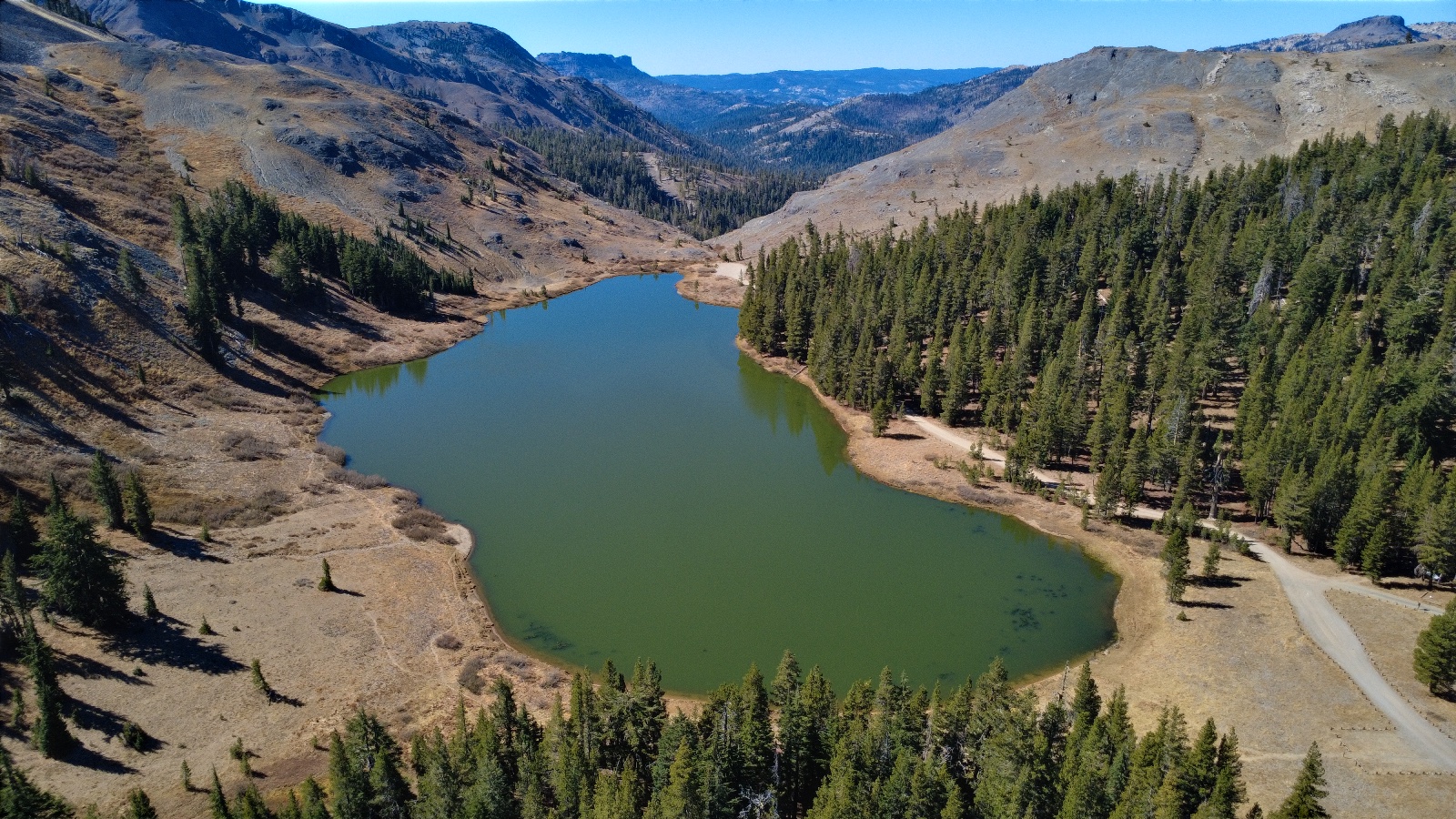 A green lake under bare slopes, a road along its edge, 11:33.