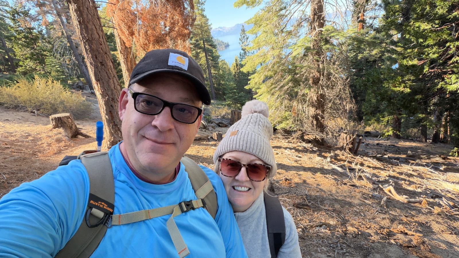 A selfie with Helena on the trail, a few rust-orange trees and a glimpse of the lake behind us.