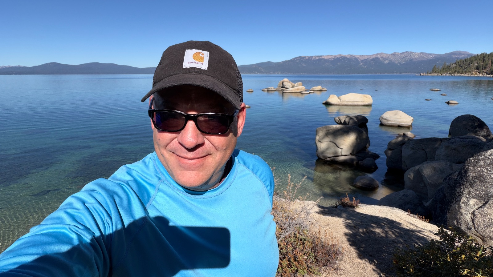 At the water's edge, with round boulders standing in the clear shallows.