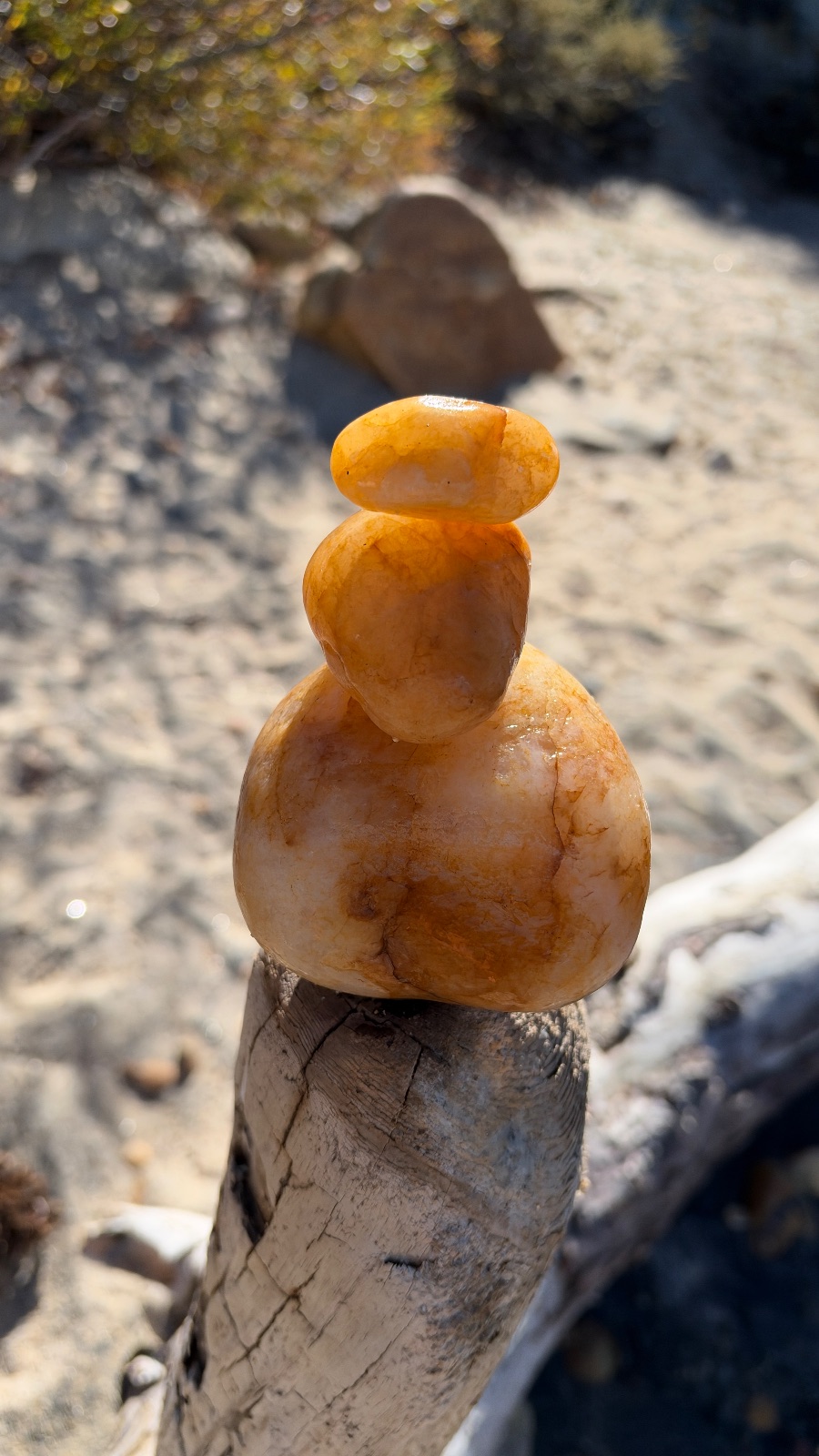 11:49. Three orange stones balanced on a driftwood post.